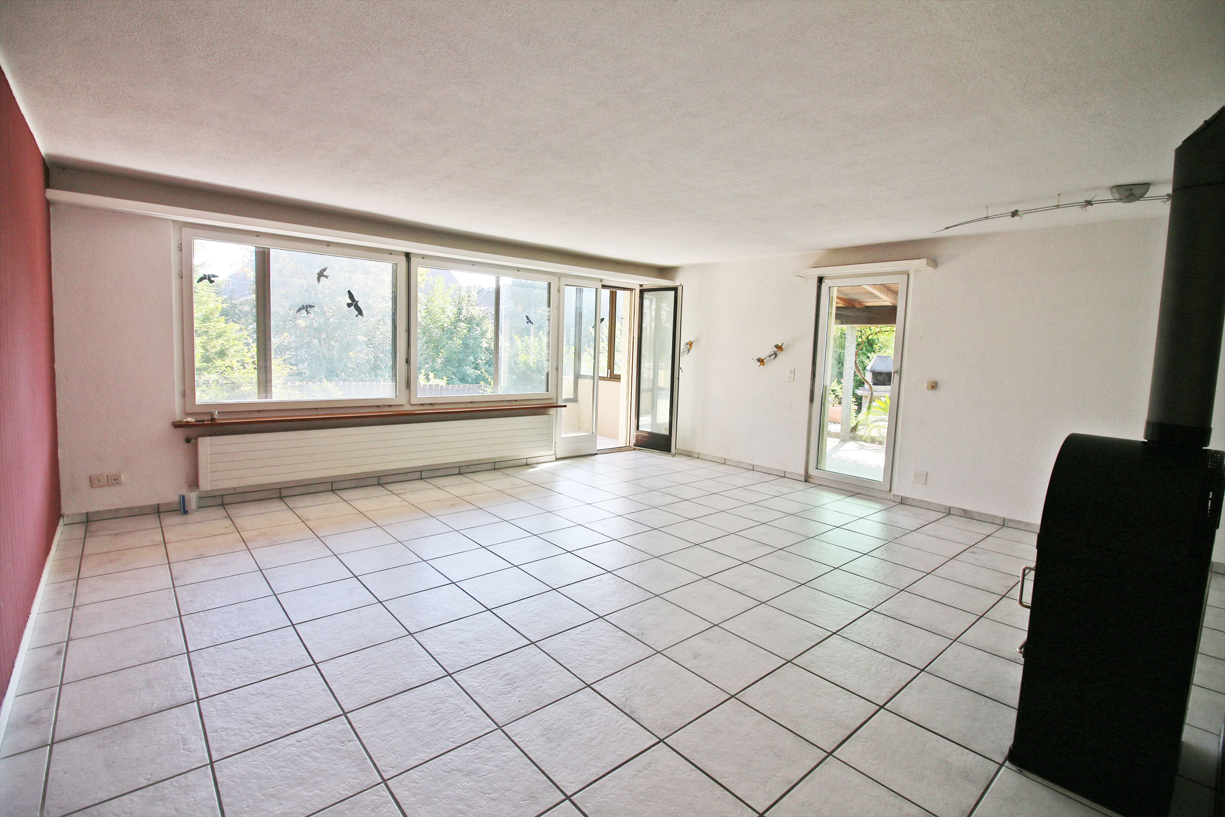 Heller Wohnraum mit Fliesenboden und großen Fensterflächen