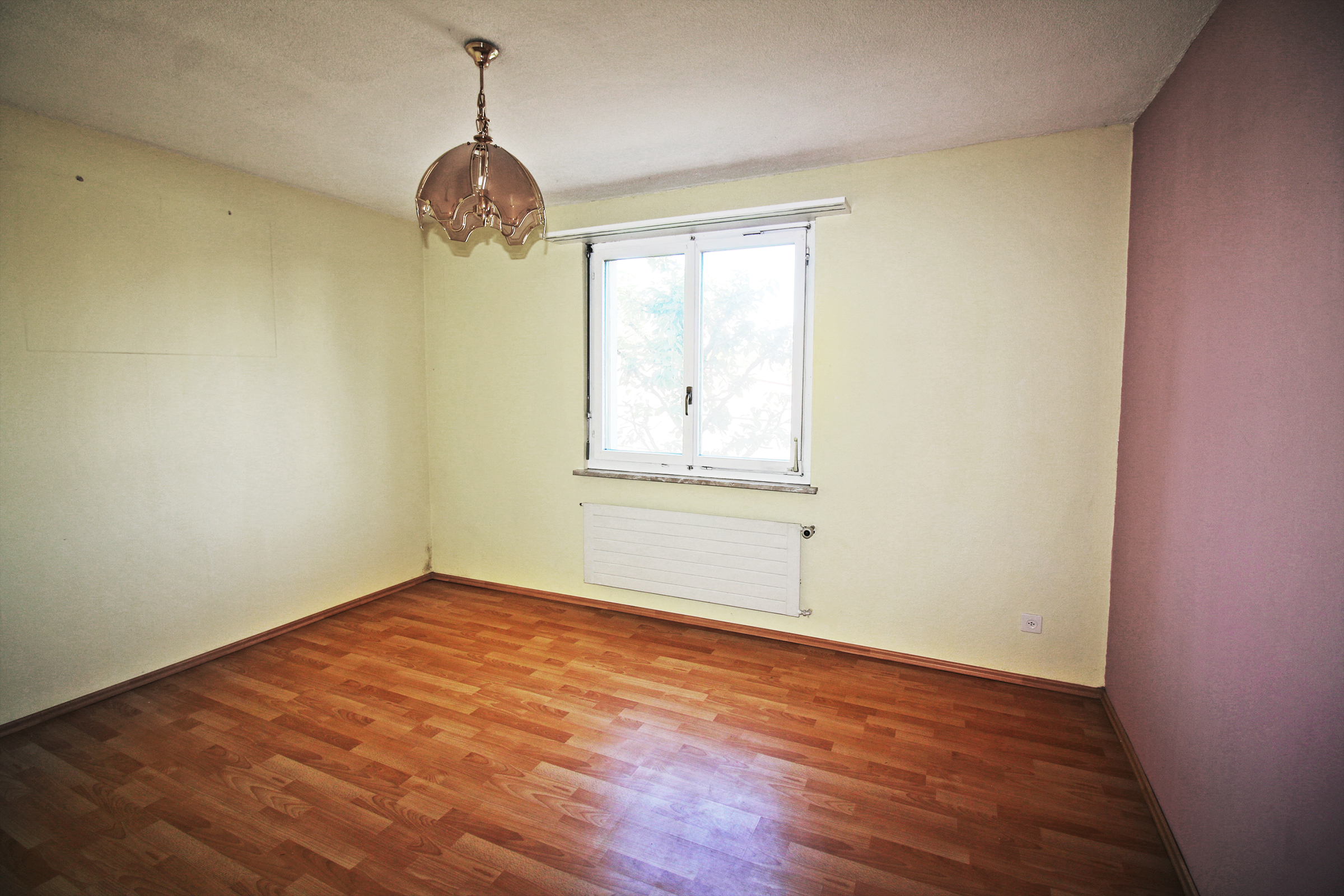Leerer Wohnraum mit Fenster und Heizkörper