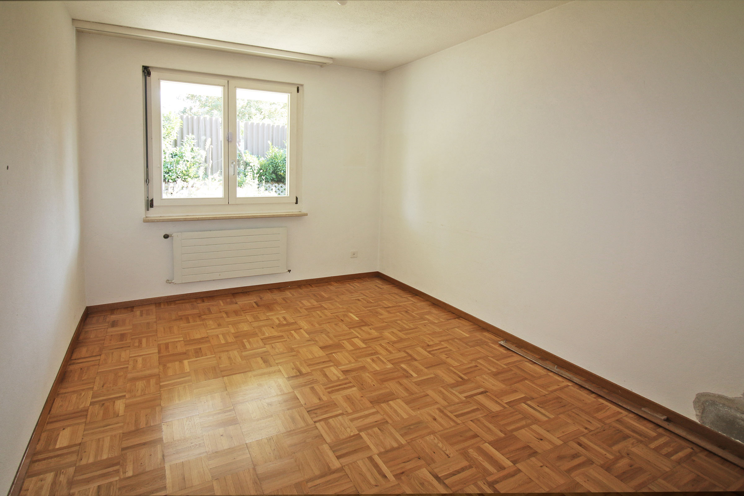 Leerer Raum mit Parkettboden und Fenster
