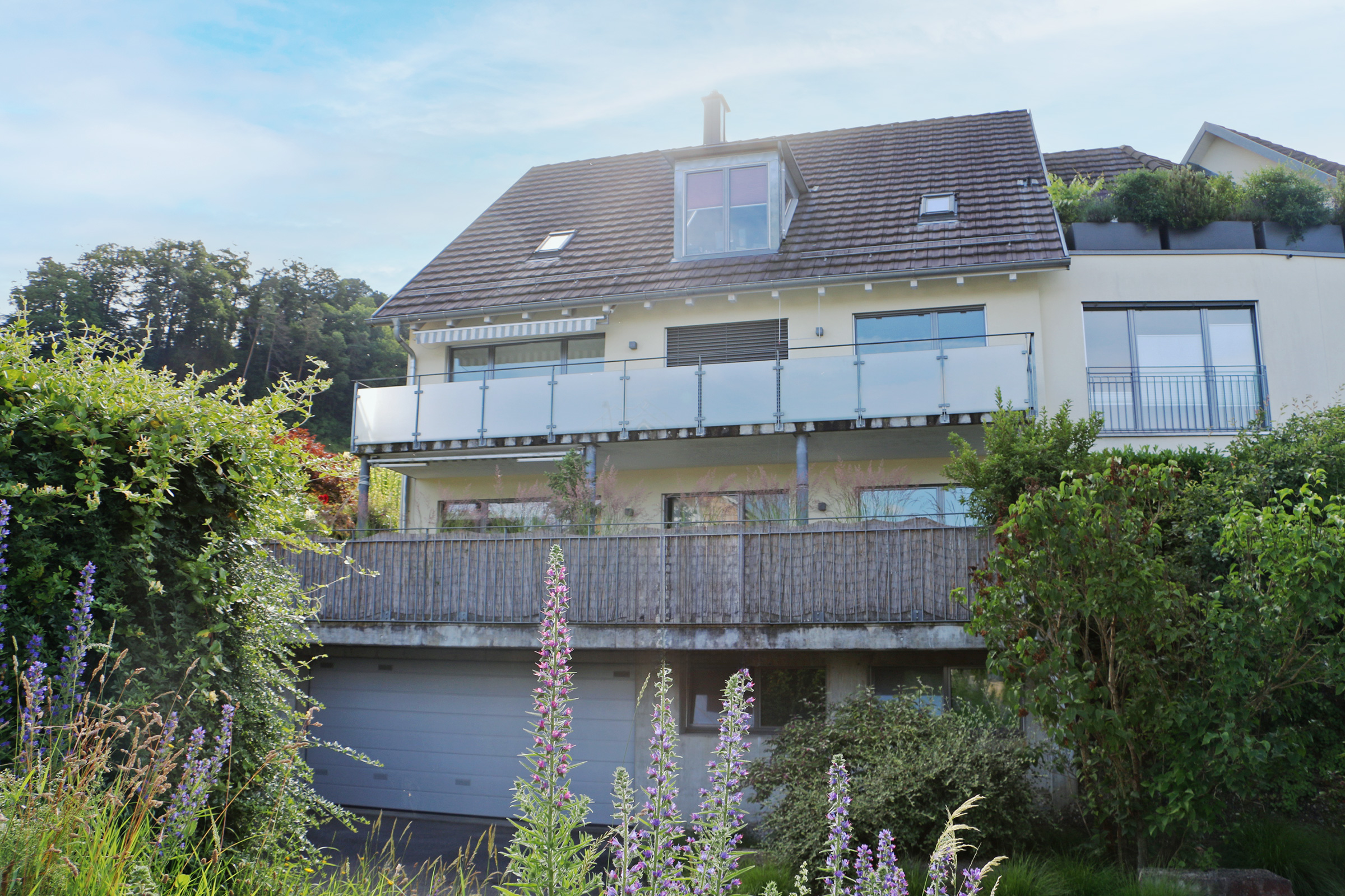 Außenansicht eines Wohnhauses mit Balkon und Garten