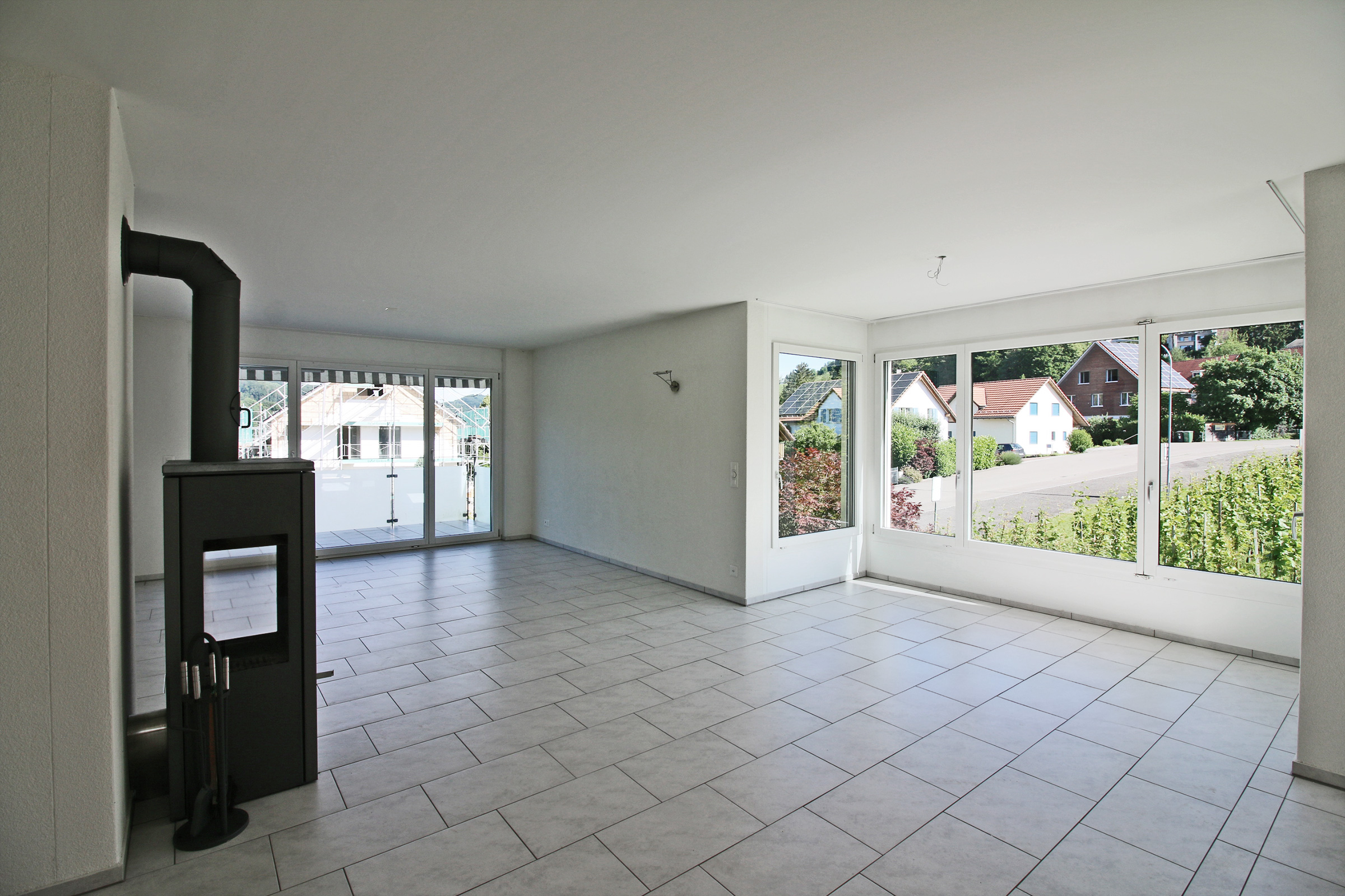 Heller Wohnraum mit Kaminofen und großen Fensterfronten