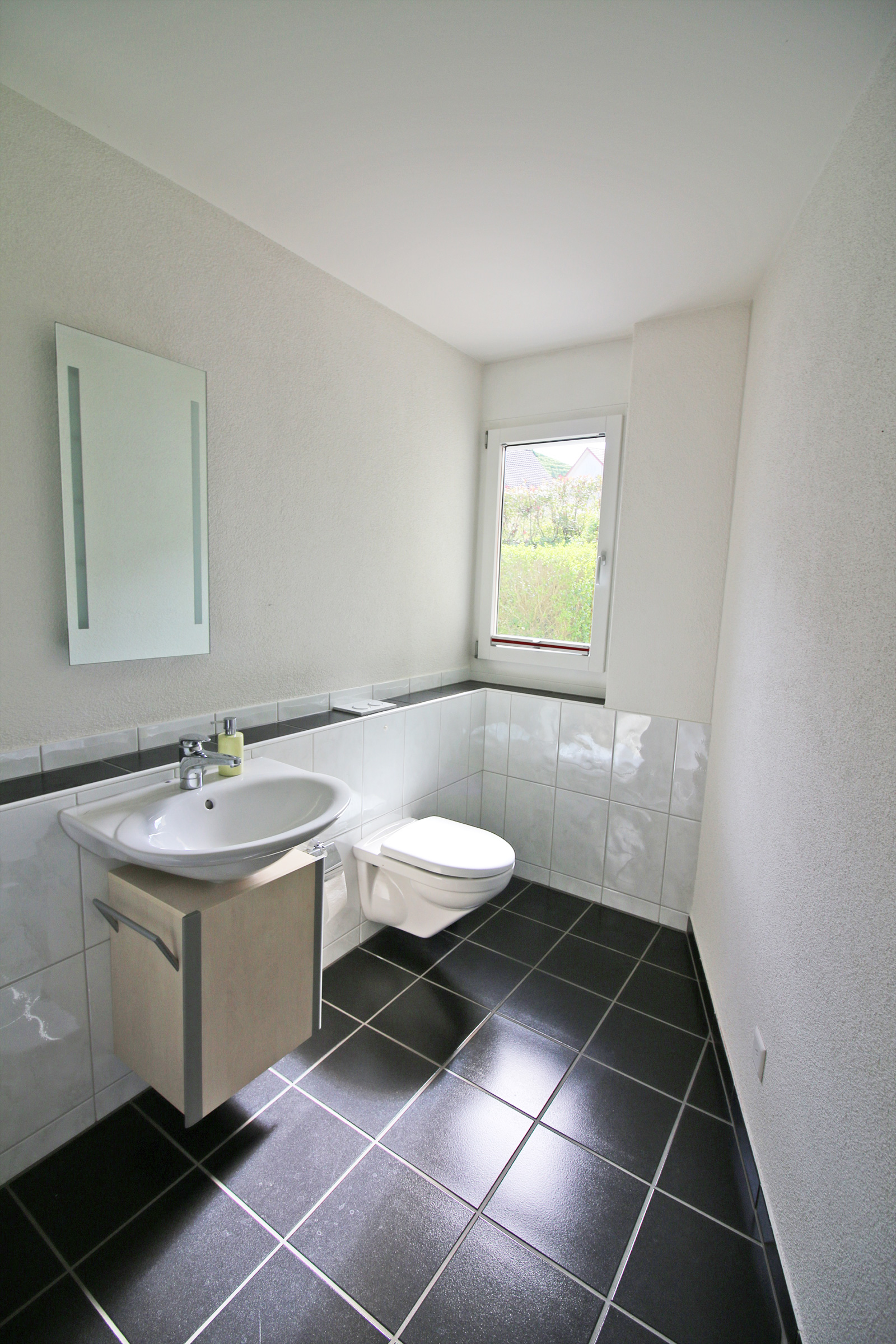 Gäste-WC mit Fenster und dunklem Fliesenboden