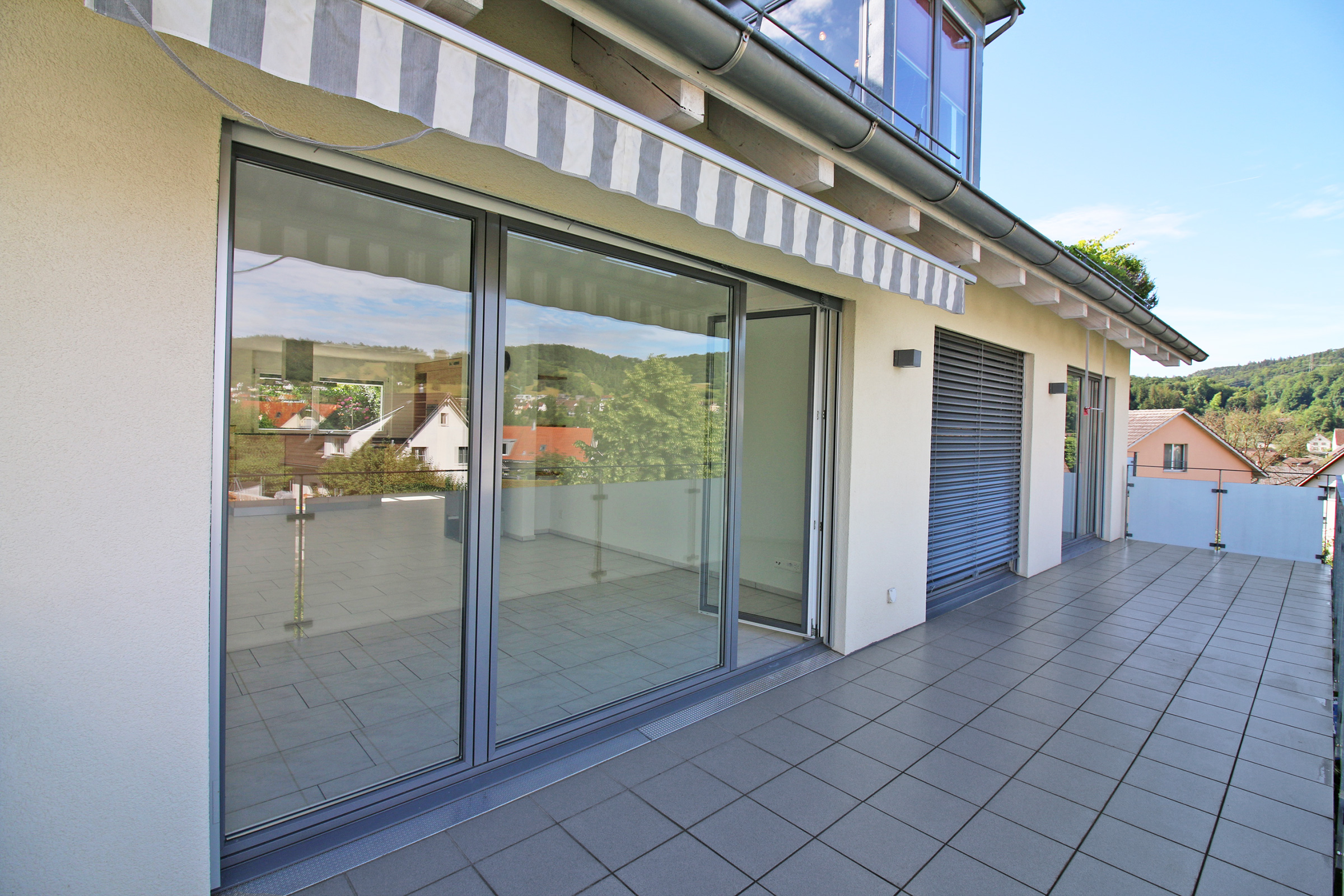 Große Dachterrasse mit Schiebetür und Blick ins Grüne