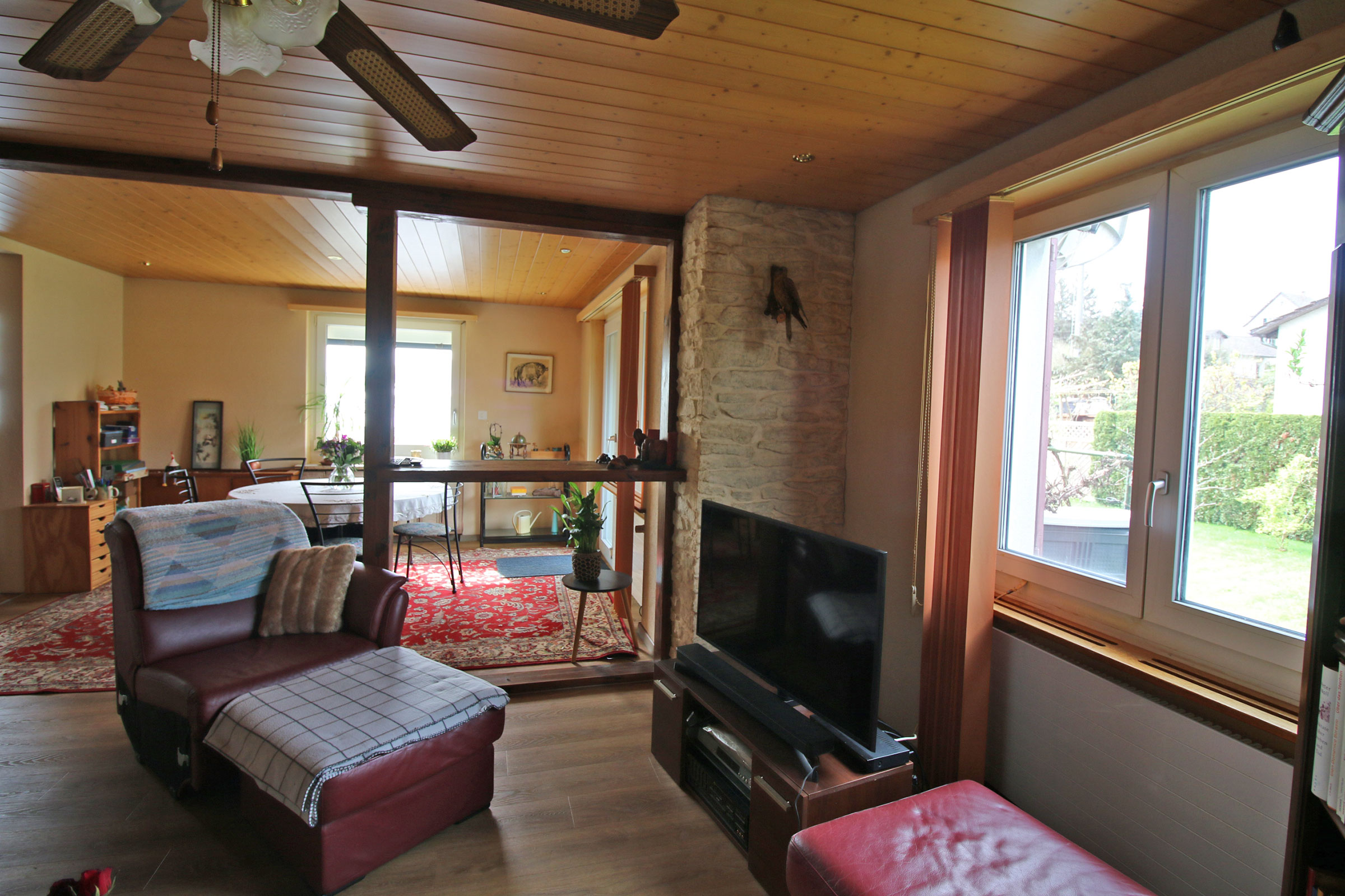 Gemütliches Wohnzimmer mit Holzdecke und Steinakzentwand
