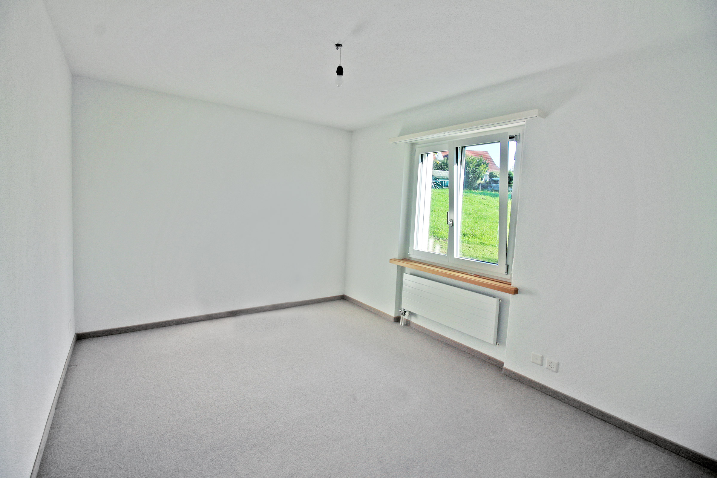 Leerer, heller Raum mit Fenster und Heizkörper