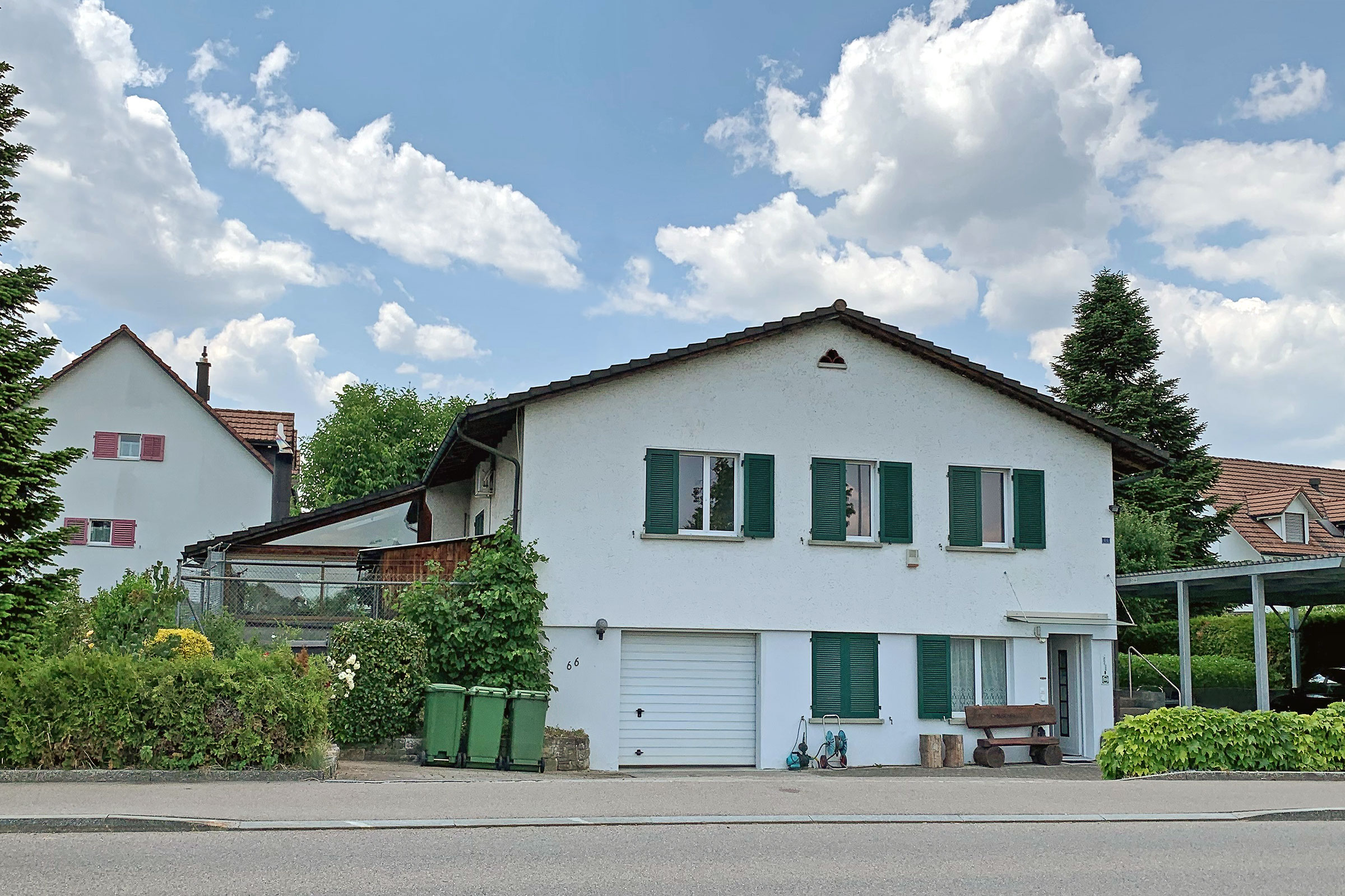 Wohnhaus mit weißer Fassade und grünen Fensterläden