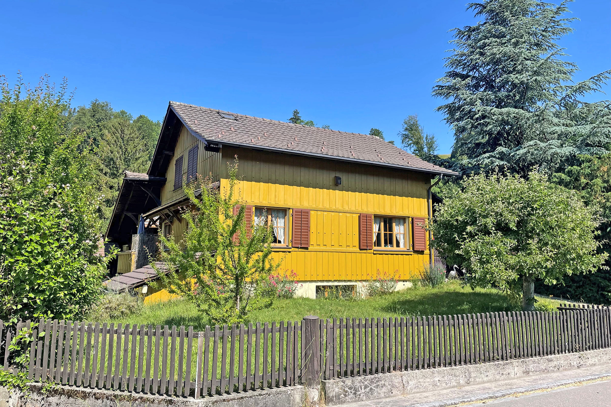 Gelbes Holzhaus in grüner Umgebung