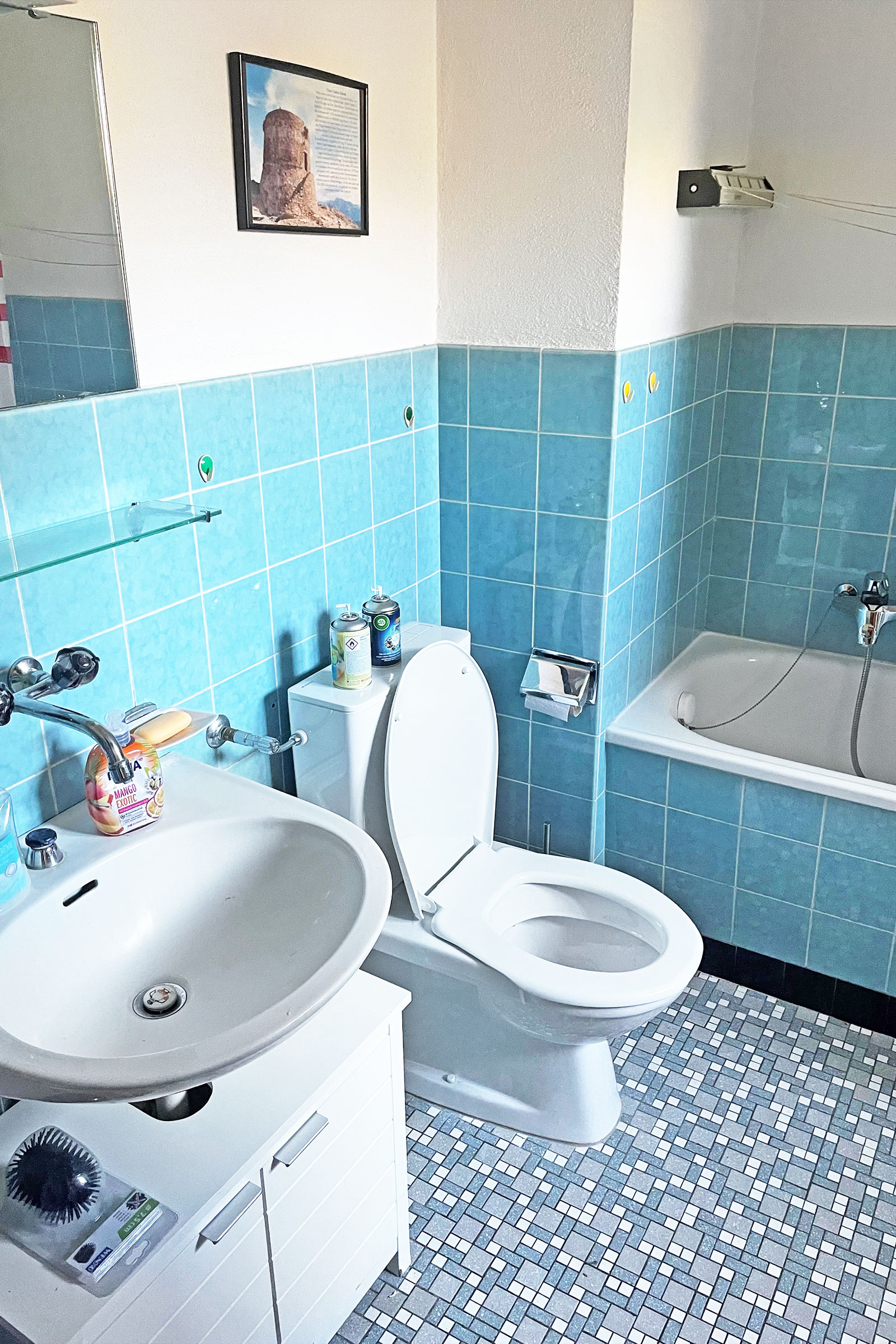 Badezimmer mit blau gefliesten Wänden und Badewanne