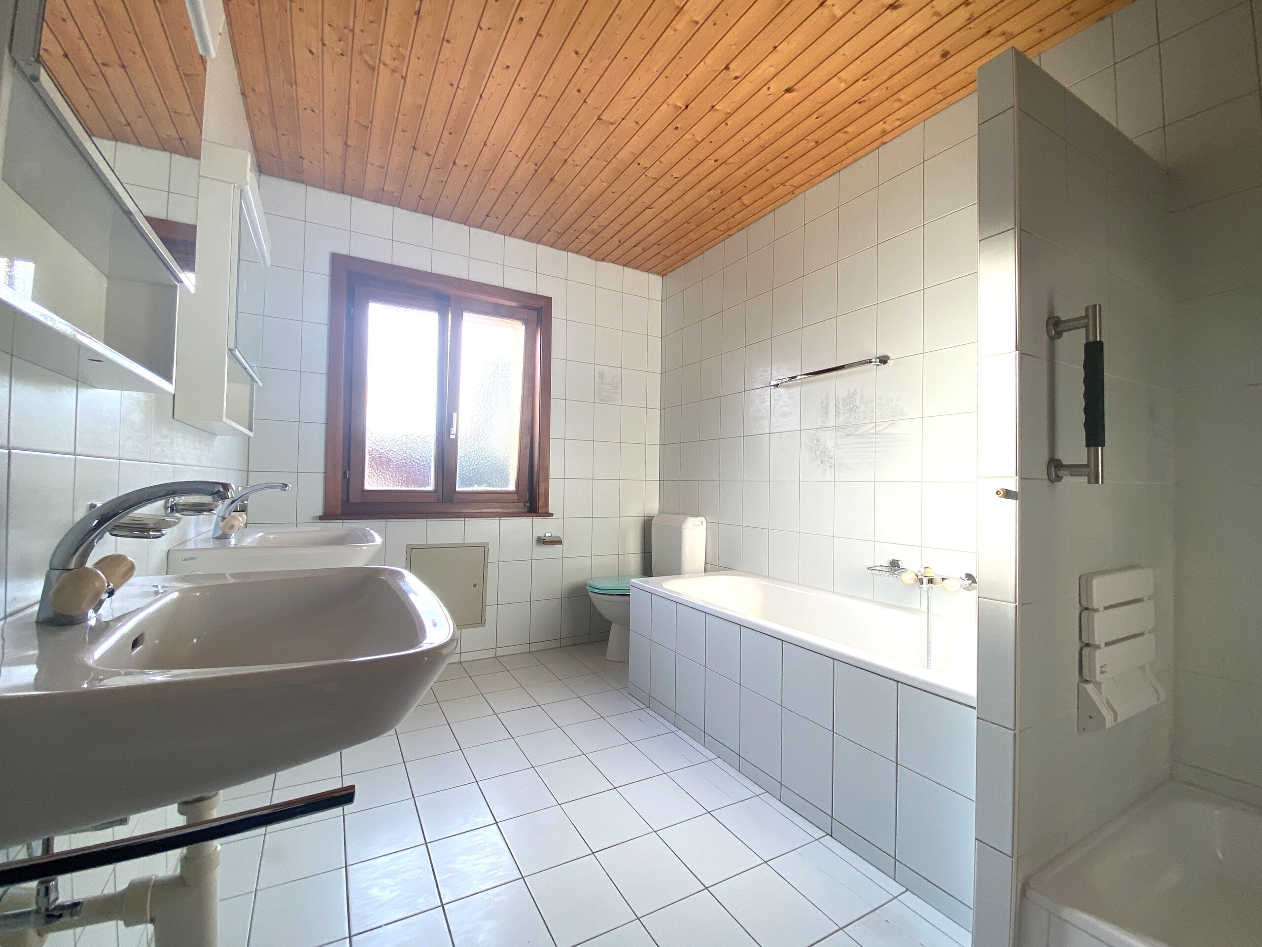 Helles Badezimmer mit Holzdecke und Badewanne