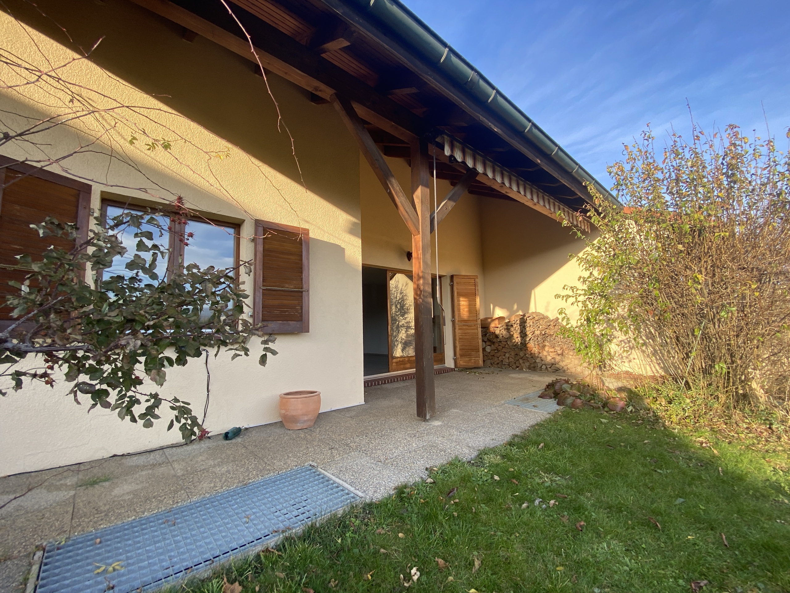 Überdachte Hausfassade mit Terrasse und Garten