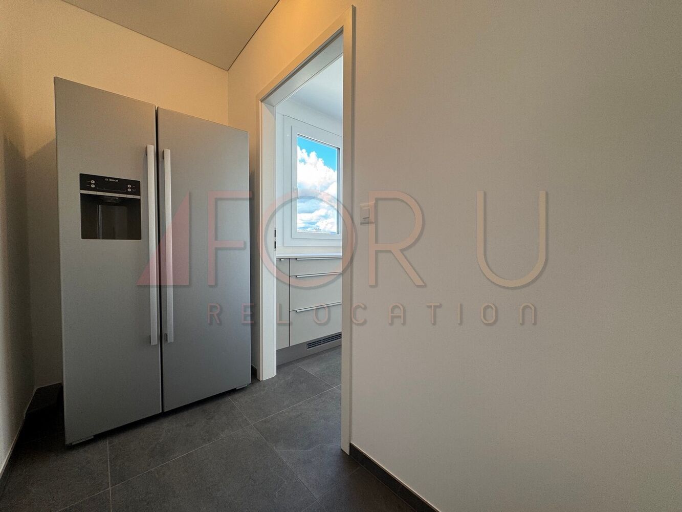 Moderne Küche mit Kühlschrank und Blick in einen Nebenraum