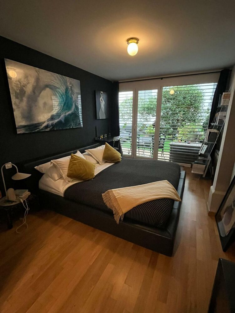 Schlafzimmer mit dunkler Akzentwand und Blick ins Grüne