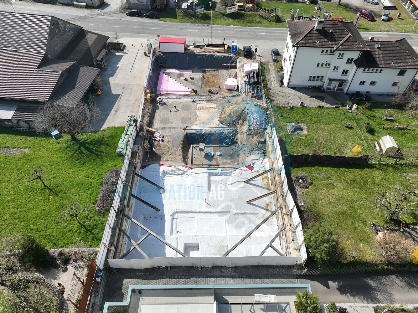 Luftaufnahme einer Baustelle mit ausgehobener Fläche und Nachbarbebauung