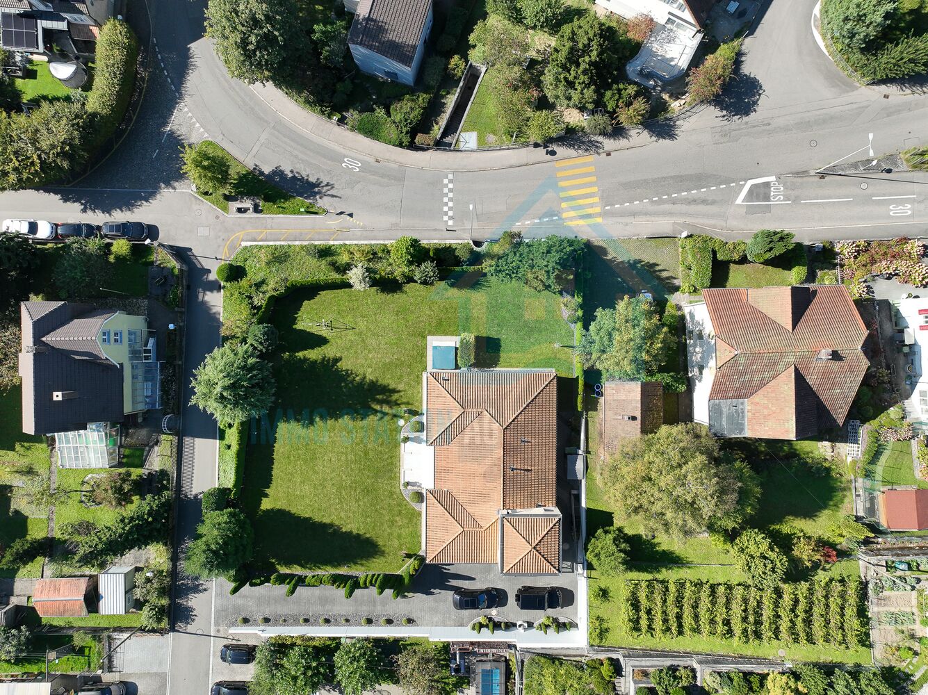 Luftaufnahme eines Wohnhauses mit großem Garten an einer Straßenkreuzung