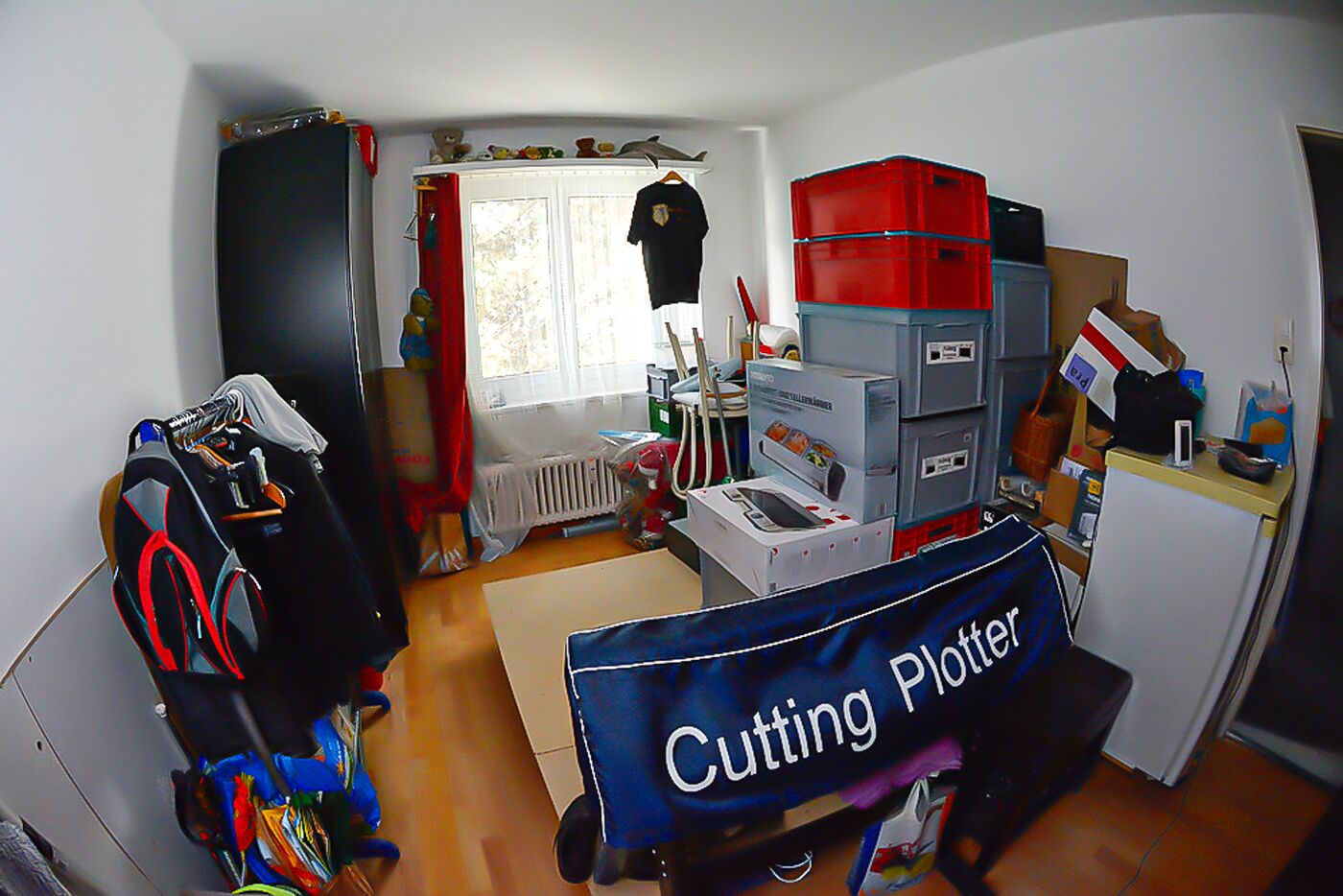 Kleines, vollgestelltes Zimmer mit Lager- und Arbeitsbereich