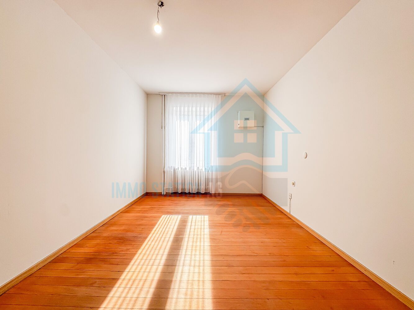 Schmaler, leerer Innenraum mit Holzboden und Tageslicht
