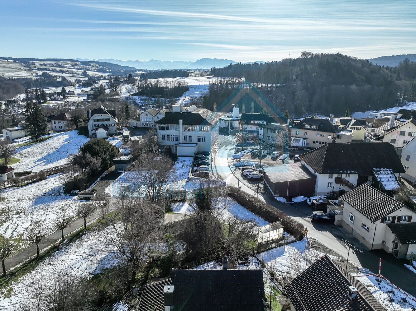 Winterliche Luftaufnahme eines Wohngebiets mit Bergpanorama