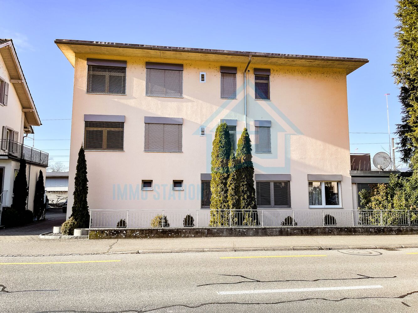 Mehrfamilienhaus mit verputzter Fassade an der Straße