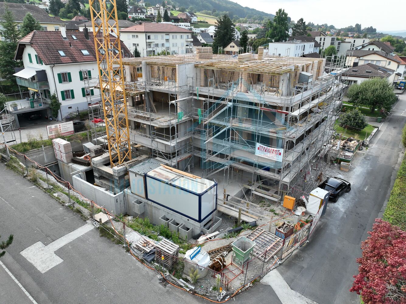 Bauphase eines Mehrfamilienhauses mit Gerüst und Kran