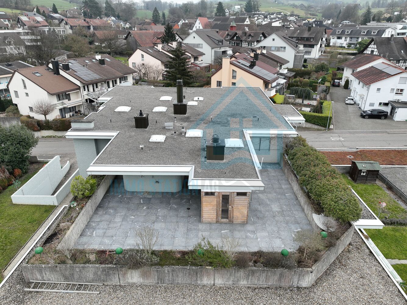 Luftaufnahme eines Wohnhauses mit Flachdach und umgebenden Einfamilienhäusern