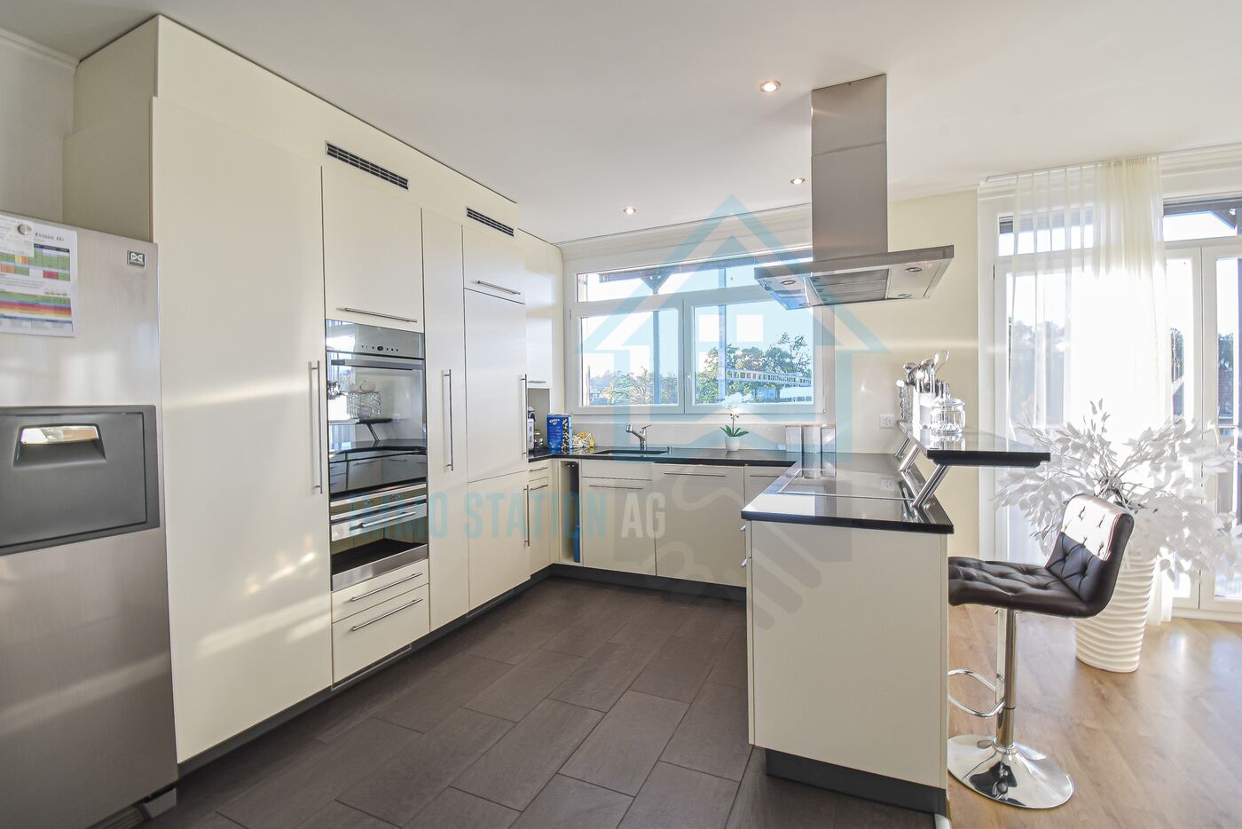 Moderne helle Küche mit Kochinsel und Edelstahlkühlschrank