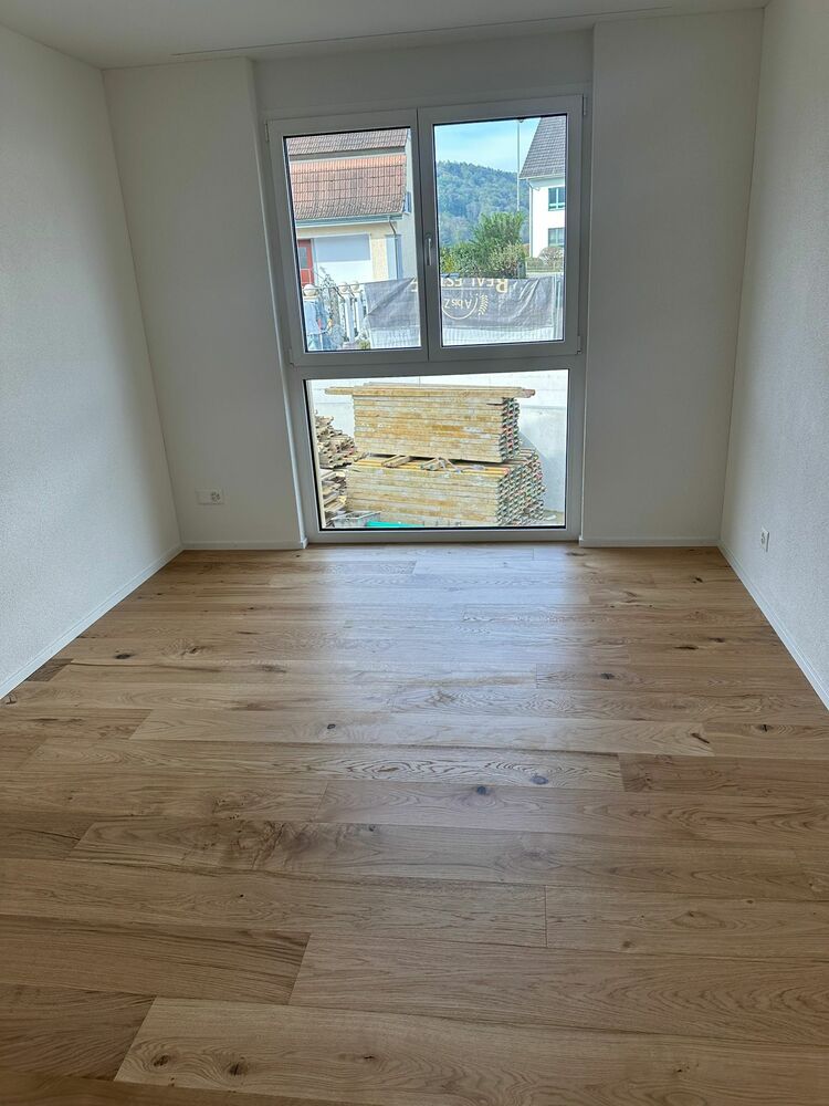 Leerer, heller Raum mit Holzfußboden und großem Fenster