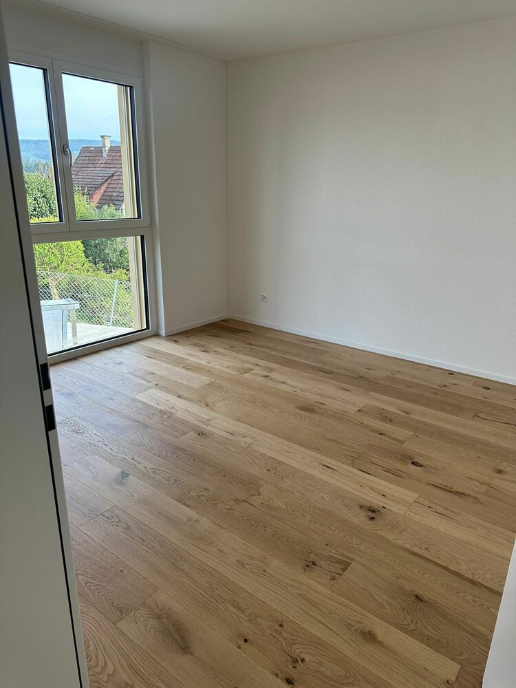 Leerer heller Raum mit großem Fenster und Holzparkett
