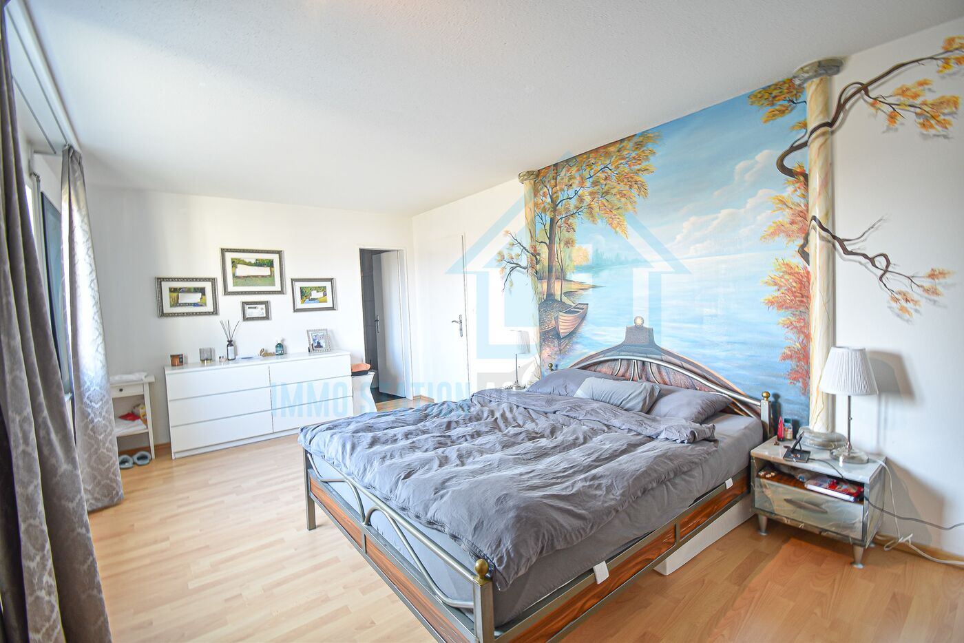 Helles Schlafzimmer mit großem Bett und Wandbild