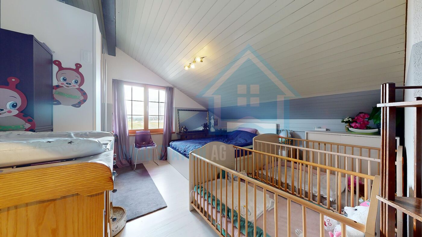 Kinderzimmer im Dachgeschoss mit zwei Betten und Kinderbett