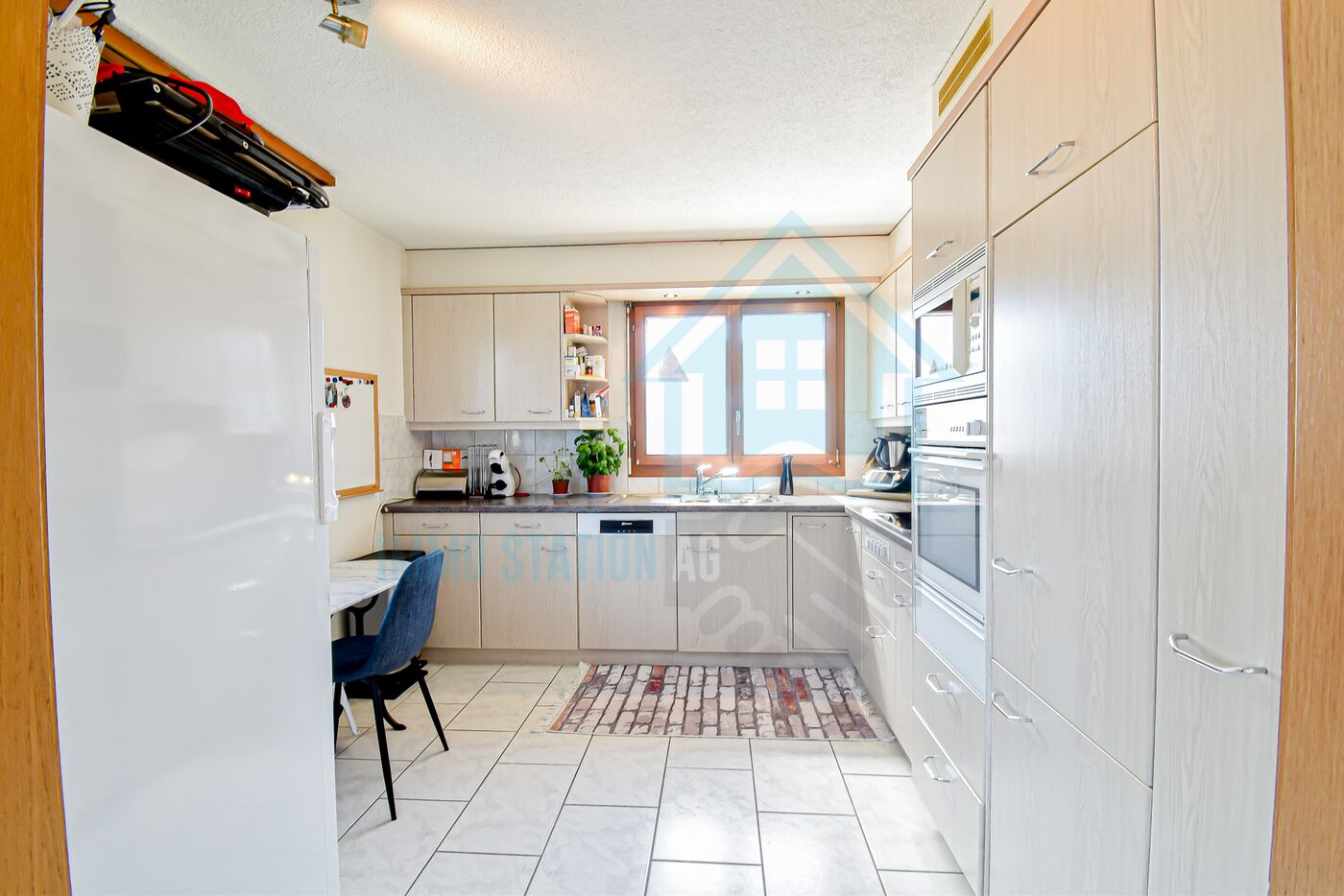 Helle Einbauküche mit Fenster und großzügigen Stauraumschränken