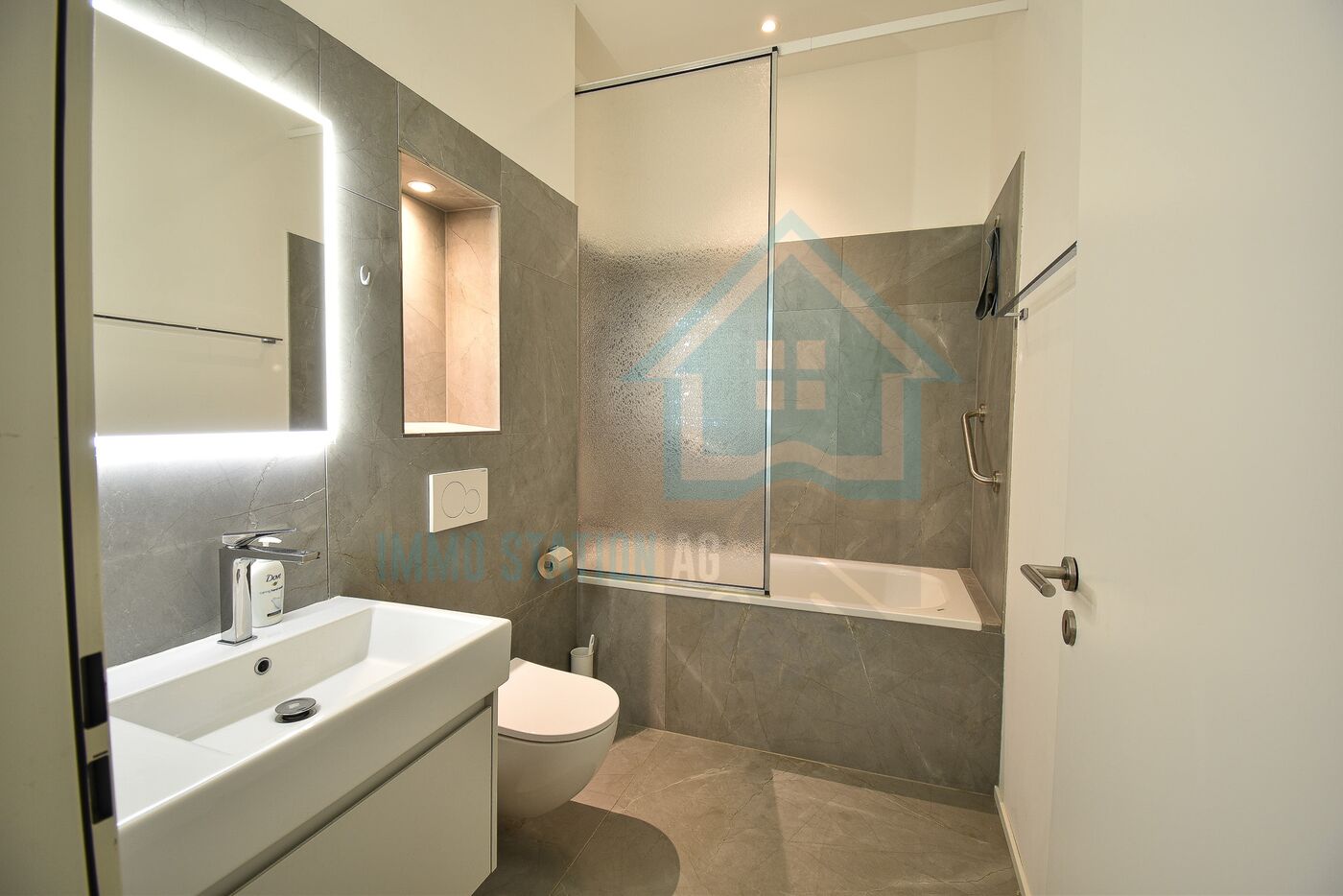 Modernes Badezimmer mit Badewanne und beleuchtetem Spiegel