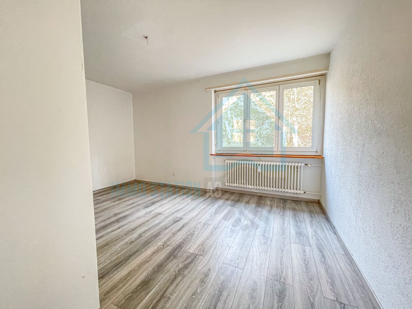 Leerer, renovierter Raum mit Fenster und Heizkörper