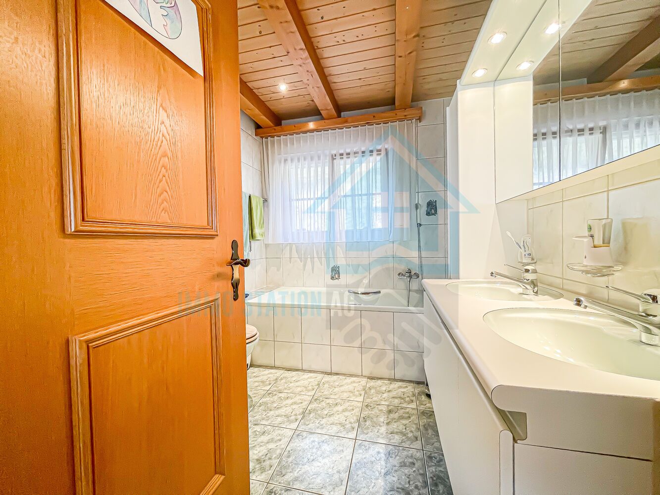 Helles Badezimmer mit Holzdecke und Doppelwaschtisch