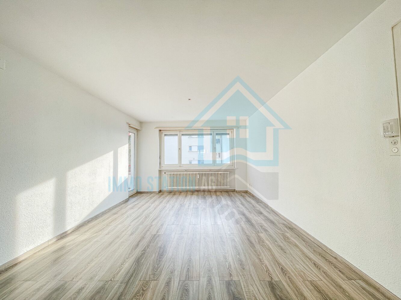 Heller leerer Wohnraum mit Laminatboden und Fensterfront