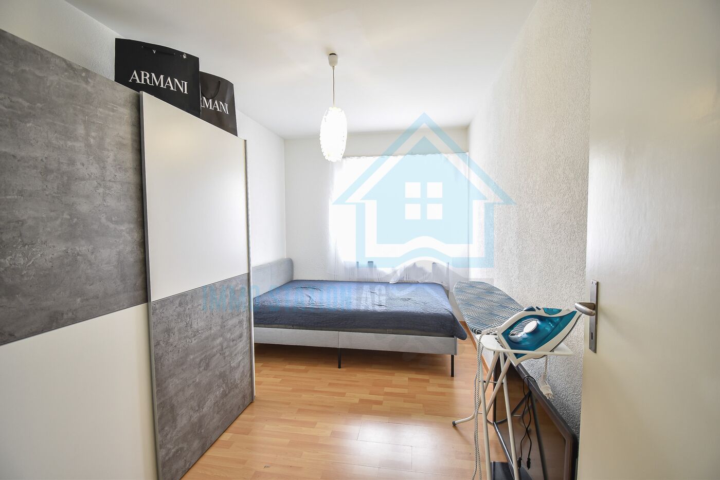 Kleines Schlafzimmer mit Bett und Bügelbrett