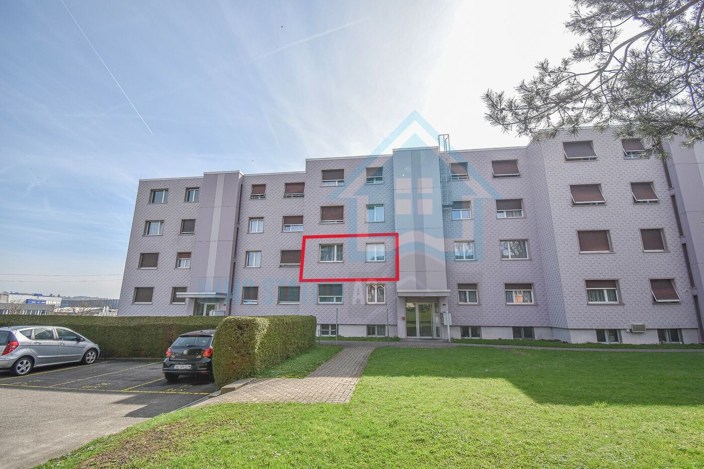 Mehrfamilienhaus mit Grünfläche und Parkplätzen