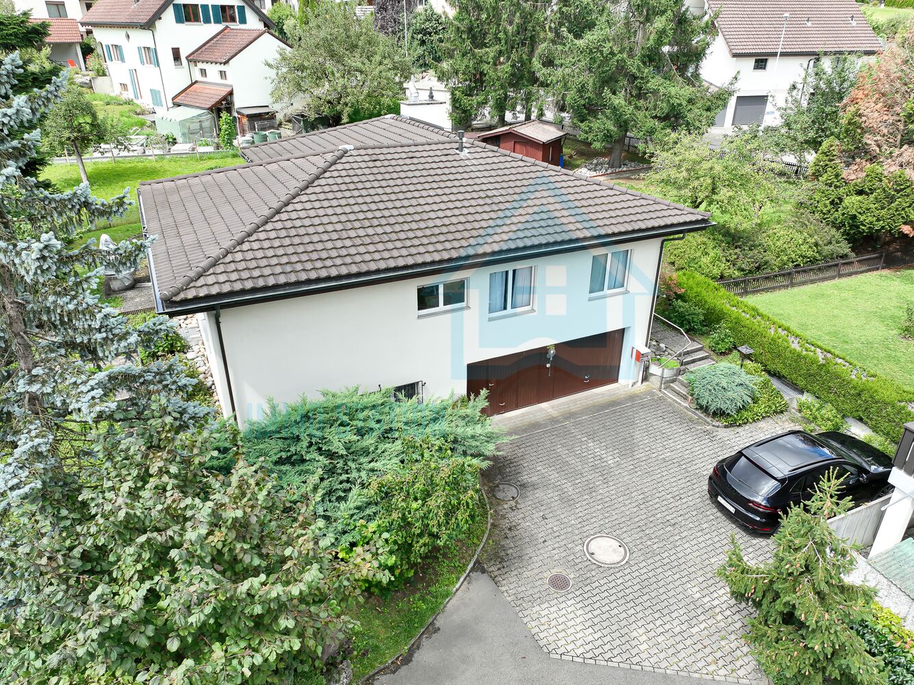 Ansicht eines Einfamilienhauses mit Einfahrt und Garten