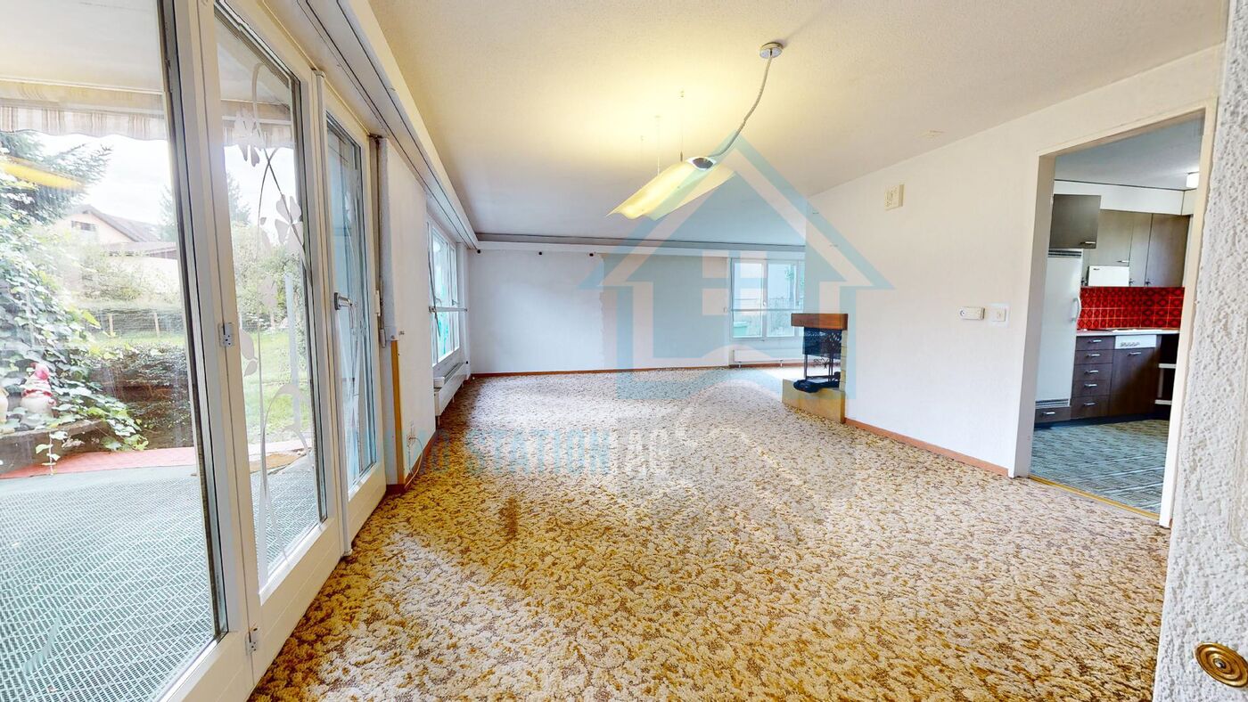 Wohnzimmer mit Zugang zur Terrasse und offenem Küchenblick