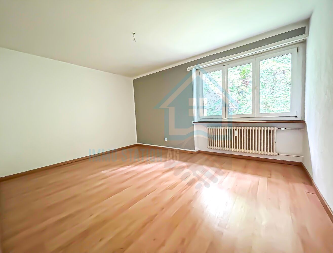 Leerer heller Wohnraum mit Fenster und Heizkörper