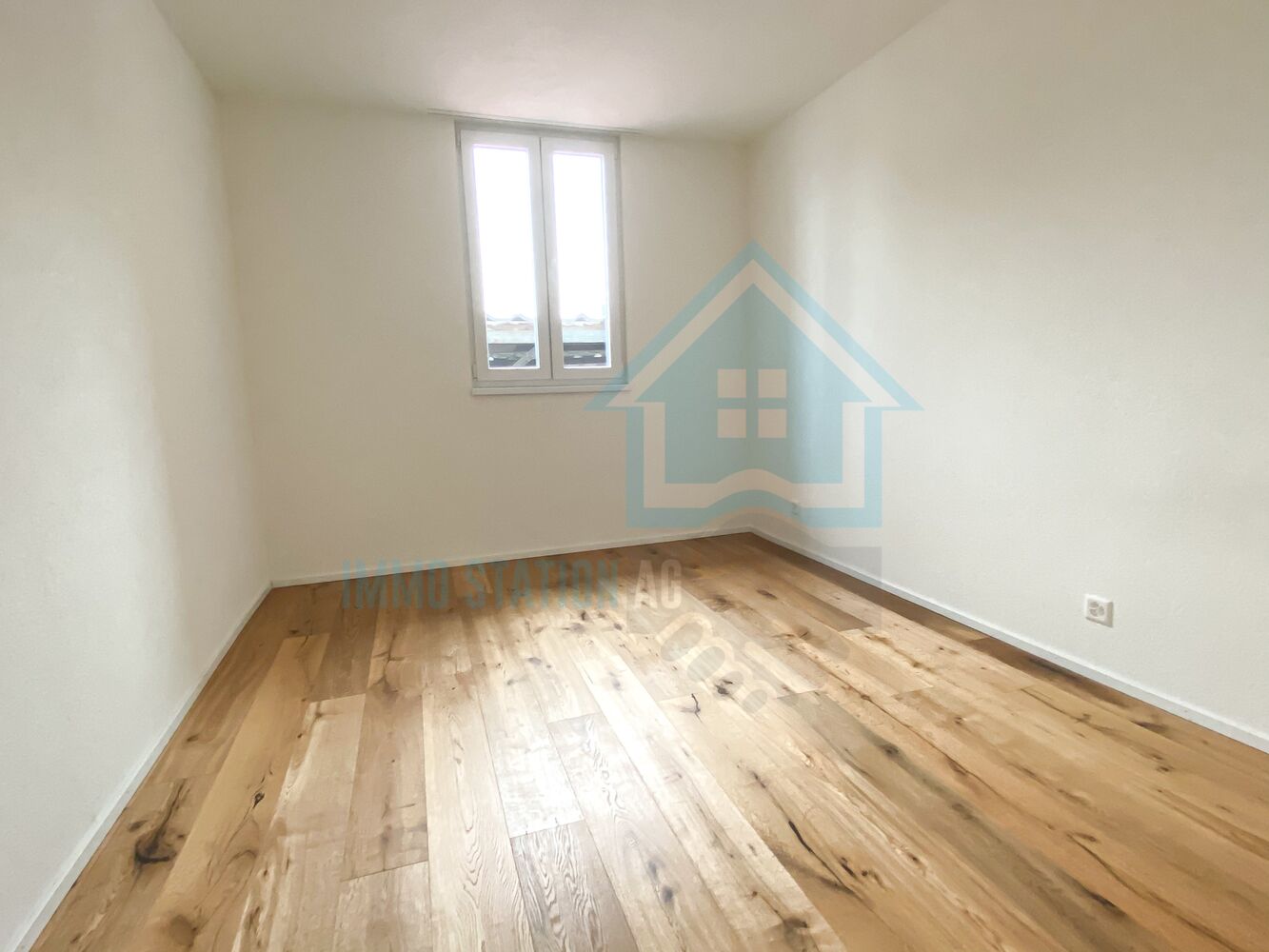 Leerer Raum mit Holzparkett und Fenster