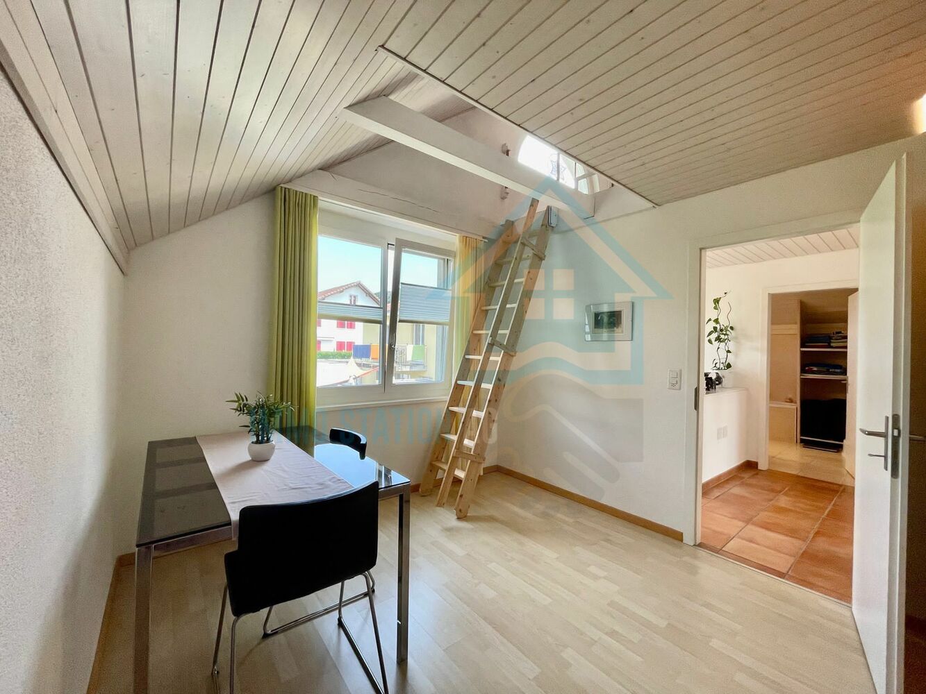 Ausgebauter Dachraum mit Arbeitsbereich und Leiter zum Dachboden