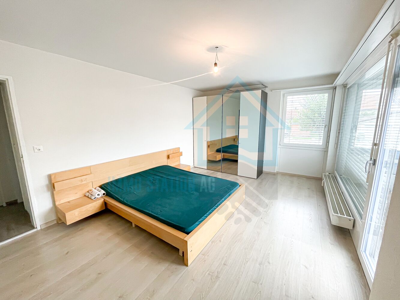 Helles Schlafzimmer mit Doppelbett und großen Fenstern
