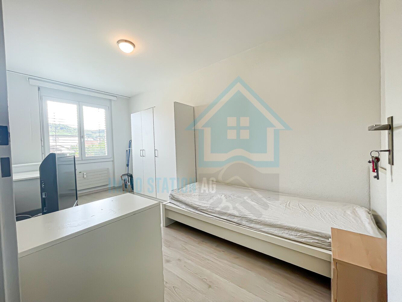 Helles Einzelzimmer mit Bett und Kleiderschrank