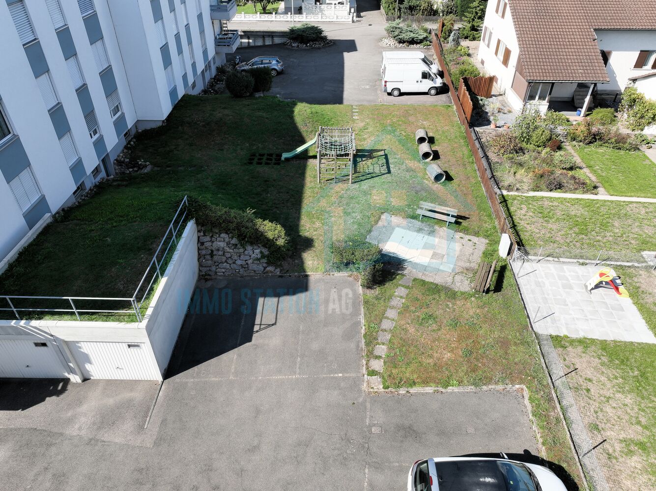 Blick auf gemeinschaftlichen Außenbereich mit Spielplatz und Stellplätzen