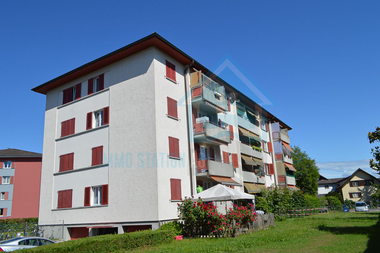 Mehrfamilienhaus mit Balkonen und roter Fensterläden