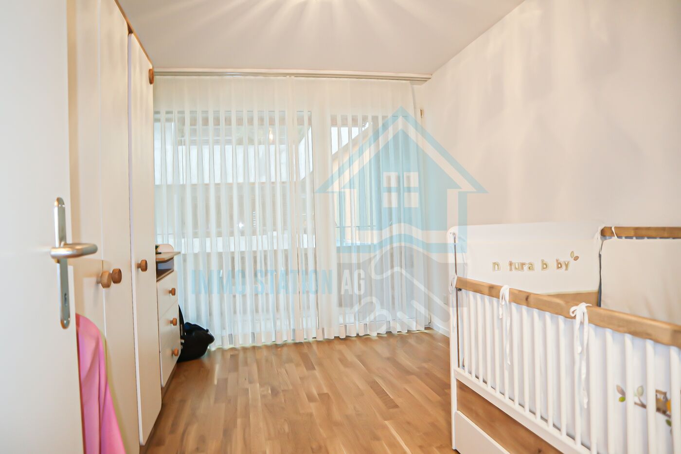 Helles Kinderzimmer mit Bettchen und Kleiderschrank