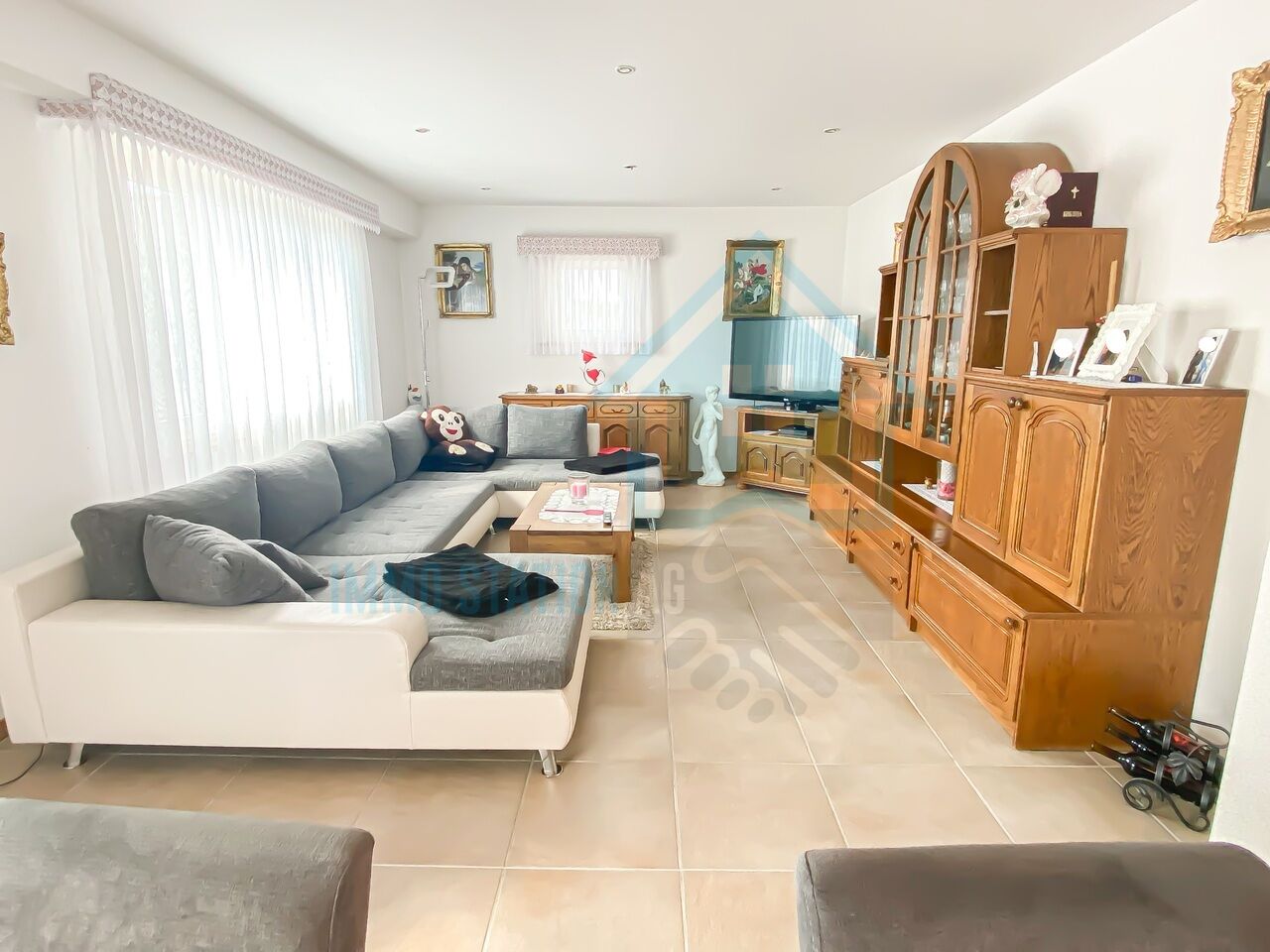 Helles Wohnzimmer mit Ecksofa und Holzvitrine