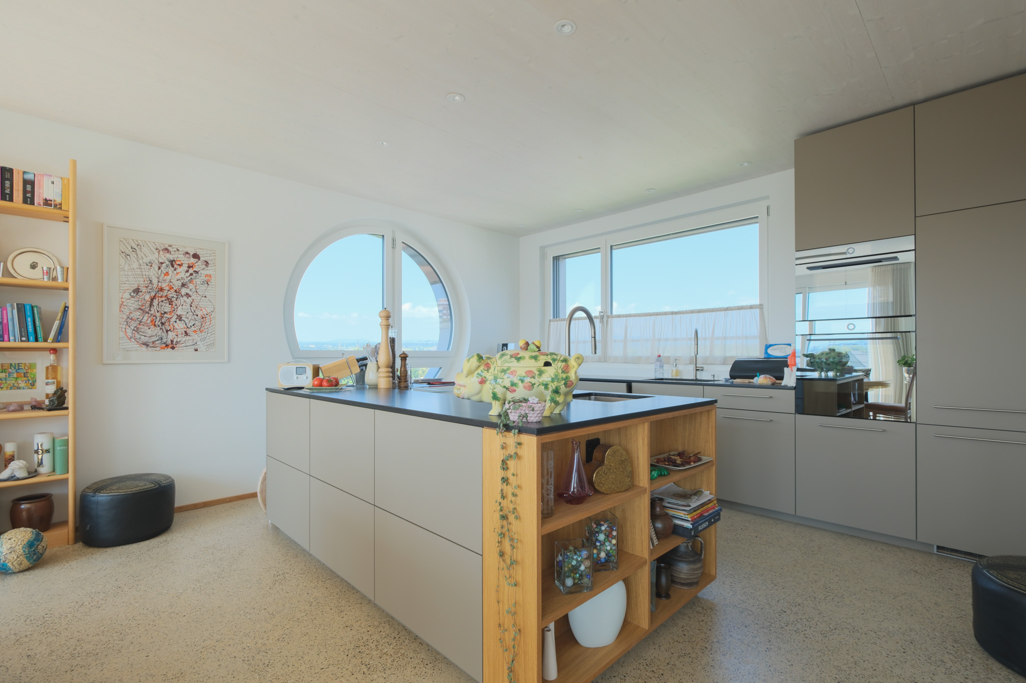 Offene Designküche mit Insel und Rundfenster