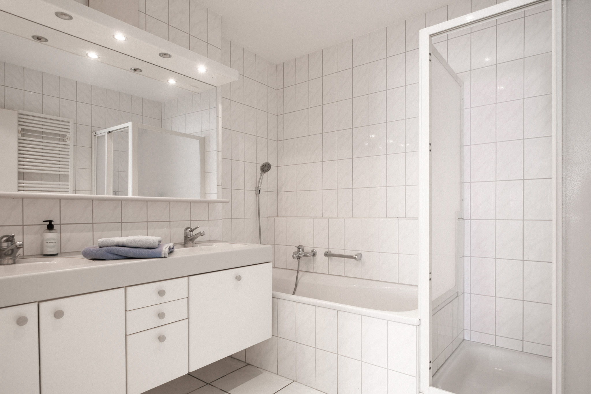 Helles weißes Badezimmer mit Badewanne und Doppelwaschtisch