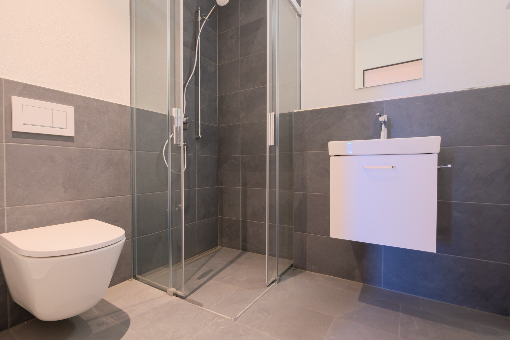 Modernes Badezimmer mit bodengleicher Dusche und wandhängendem WC